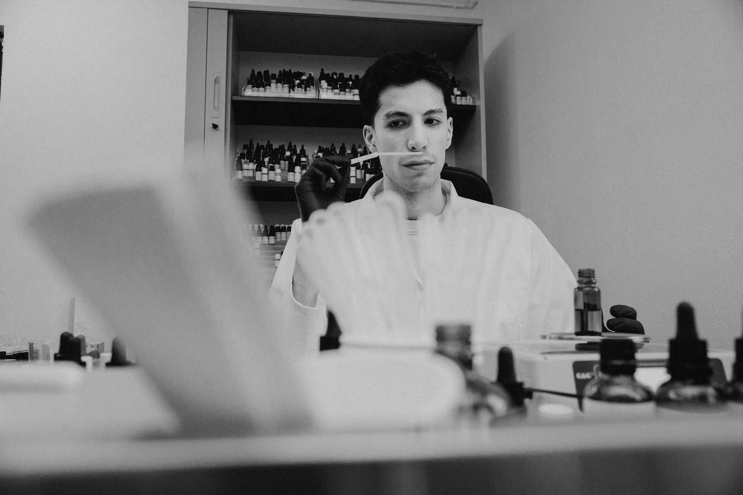 rodi çiçek sitzt am arbeitstisch im atelier und riecht an einem duftstreifen
